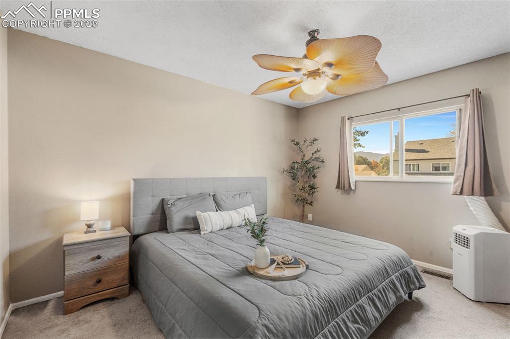 Image 14 of 29: Bedroom with light colored carpet, a ceiling fan, and a textured ceiling
