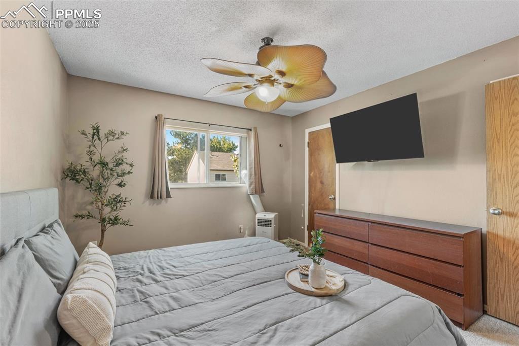 Image 15 of 29: Bedroom featuring a textured ceiling, ceiling fan, and carpet