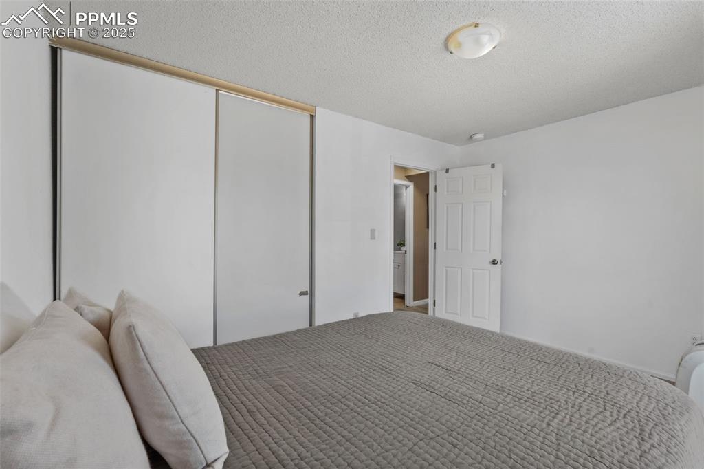 Image 19 of 29: Carpeted bedroom featuring a textured ceiling and a closet