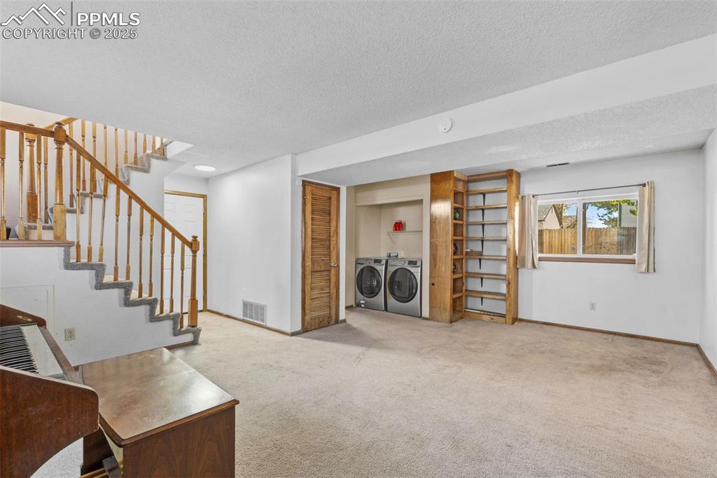 Image 21 of 29: Sitting room with carpet flooring, separate washer and dryer, a textured ce