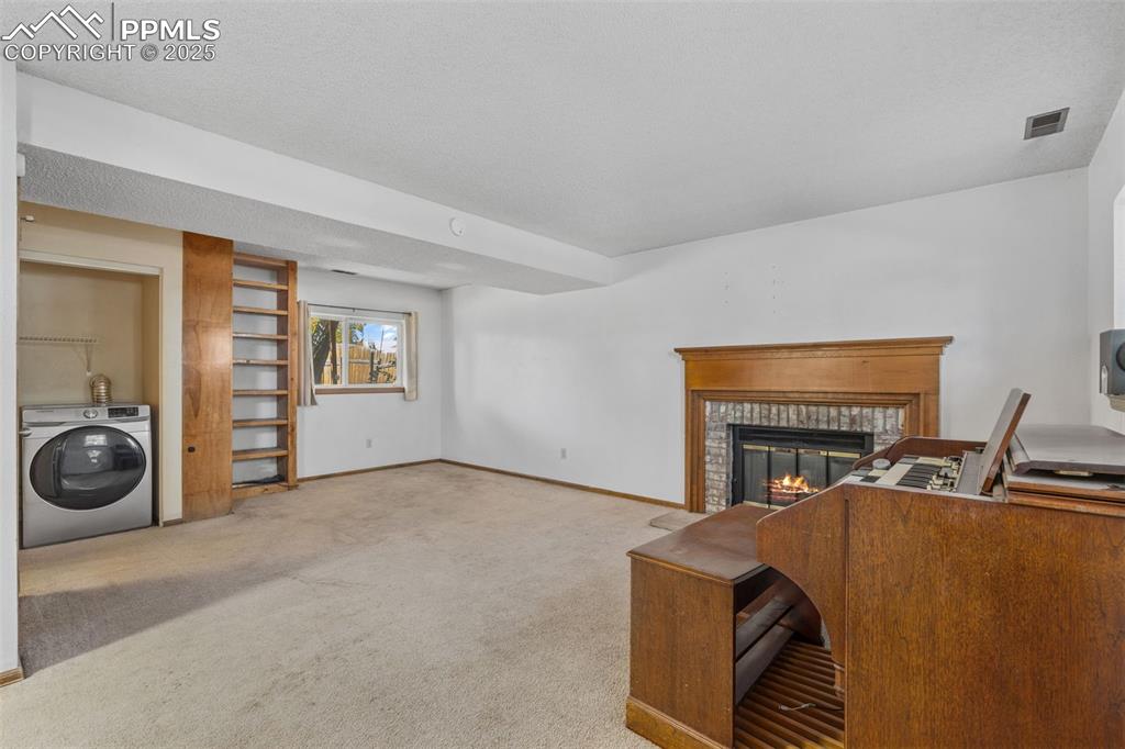 Image 22 of 29: Office area with washer / dryer, a glass covered fireplace, carpet flooring