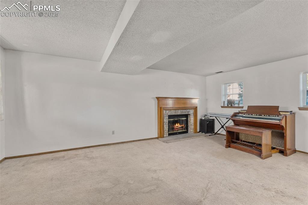 Image 23 of 29: Living room with light colored carpet, a fireplace, and a textured ceiling