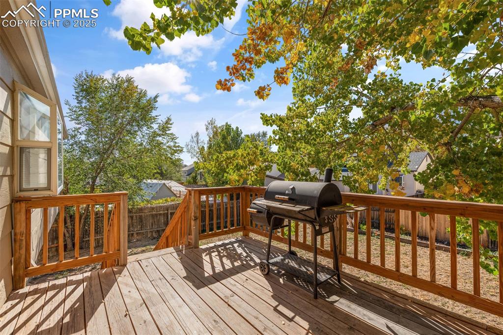 Image 25 of 29: Wooden terrace featuring area for grilling and a fenced backyard