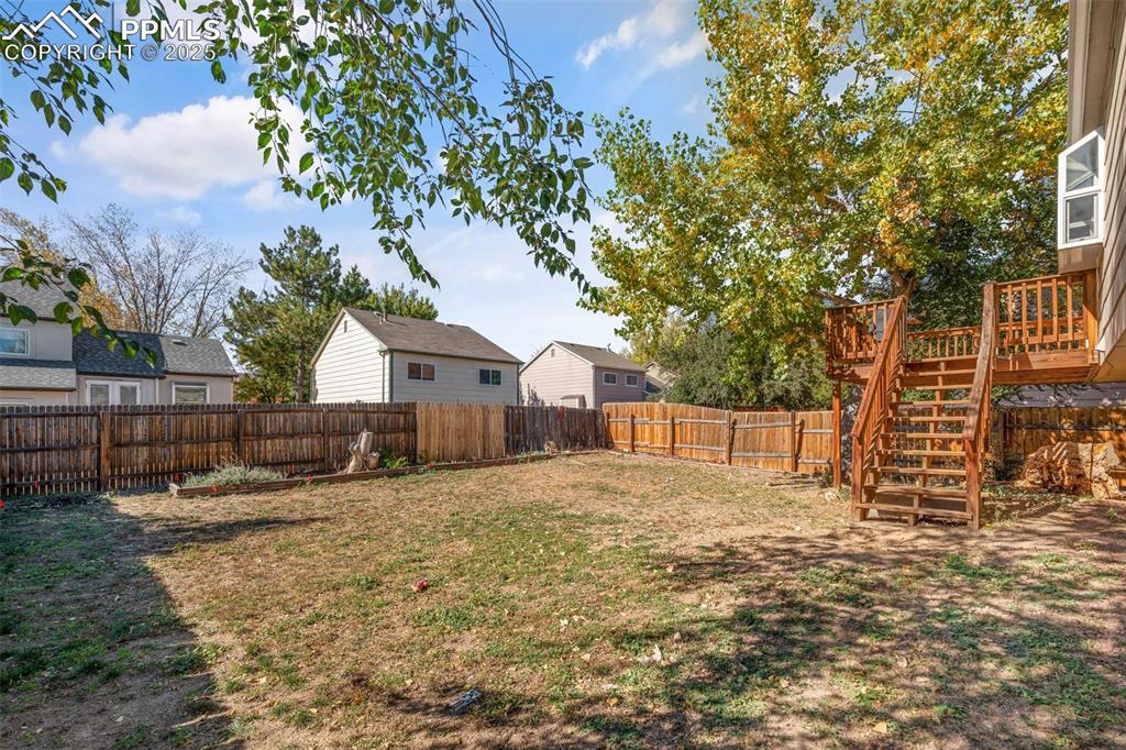 Image 26 of 29: Fenced backyard with a wooden deck and stairway