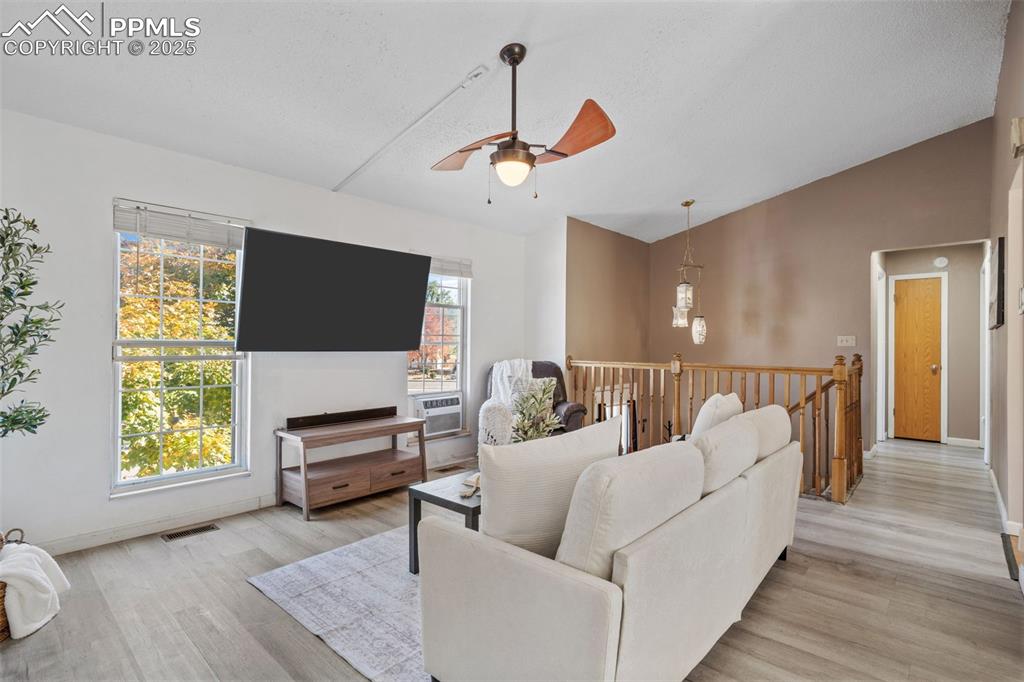 Image 6 of 29: Living room with a ceiling fan, light wood-type flooring, lofted ceiling, a
