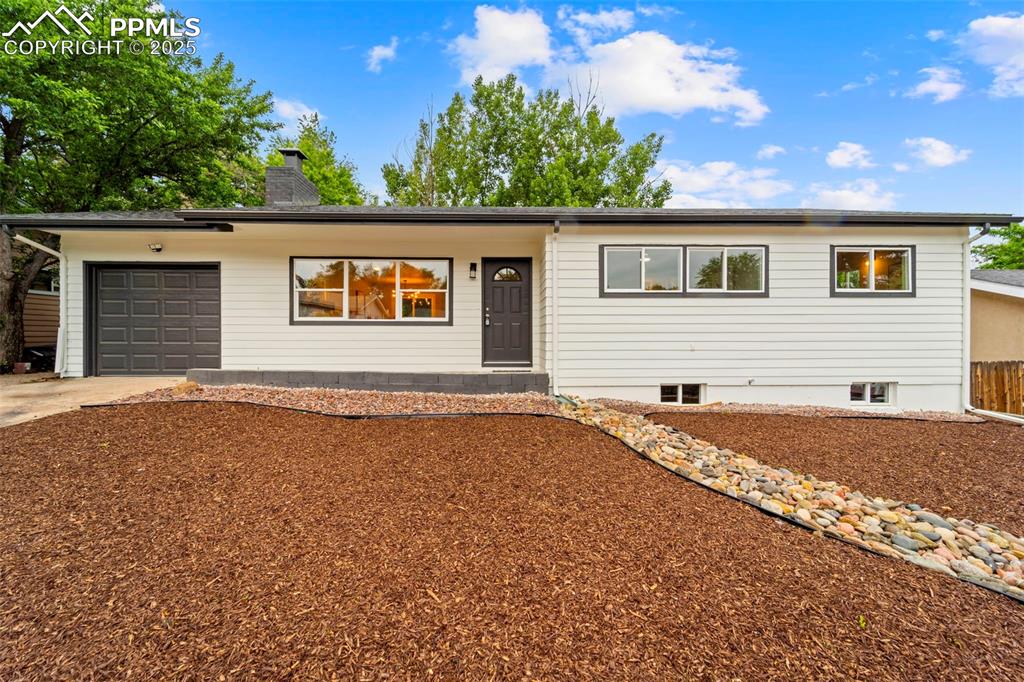 Caption: Ranch-style house with driveway, an attached garage, and a chimney, new landscaping