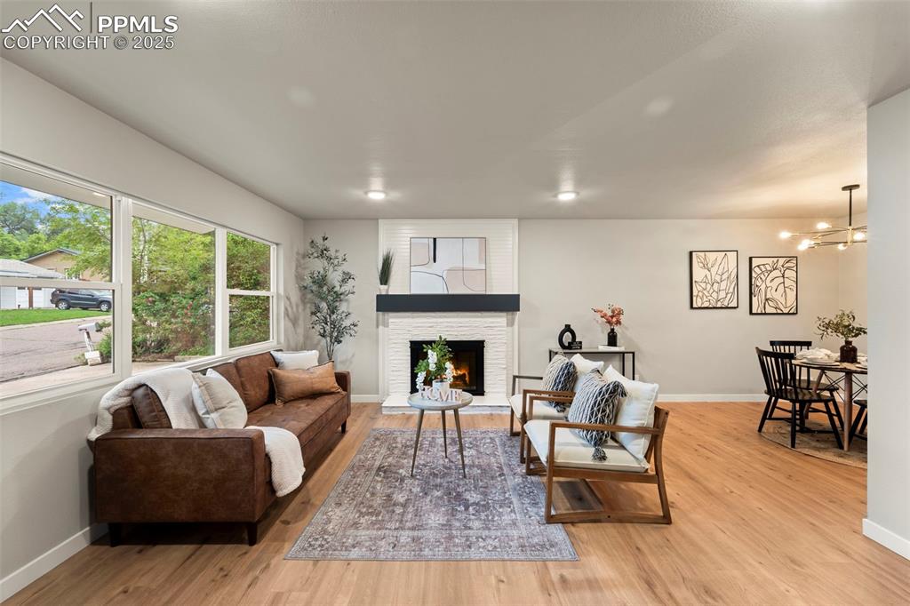 Image 10 of 31: Living area featuring light wood-style flooring, baseboards, a large firepl