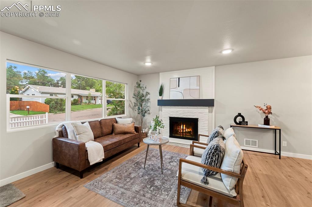 Image 11 of 31: Living area featuring baseboards, wood finished floors, a fireplace, and re