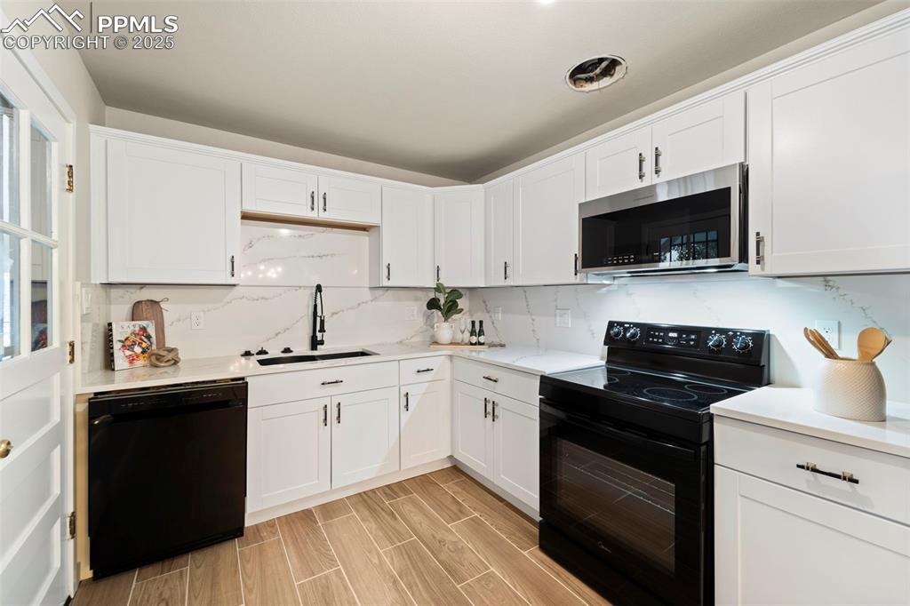 Image 15 of 31: Kitchen with black appliances, a sink, and white cabinets