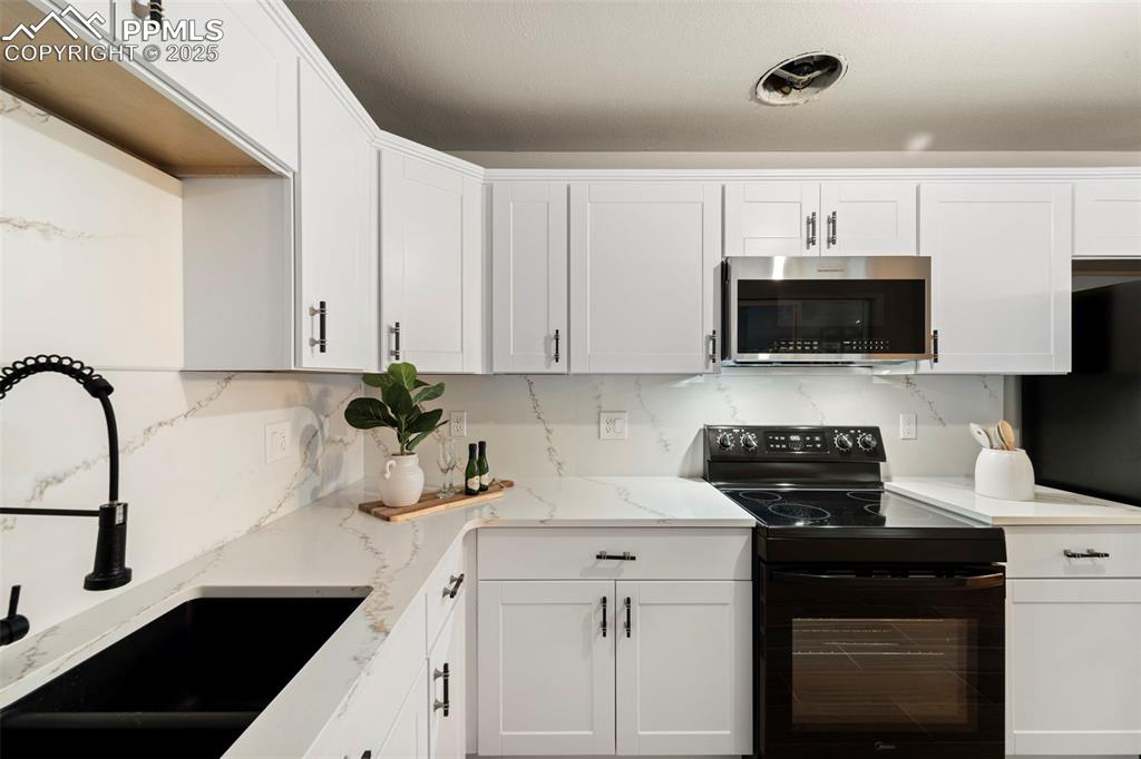 Image 16 of 31: Kitchen with stainless steel microwave, black range with electric cooktop, 