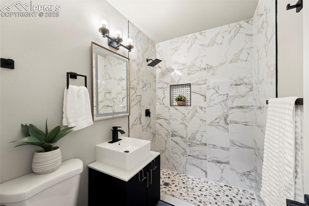 Image 17 of 31: Full bathroom with toilet, tiled shower, and vanity
