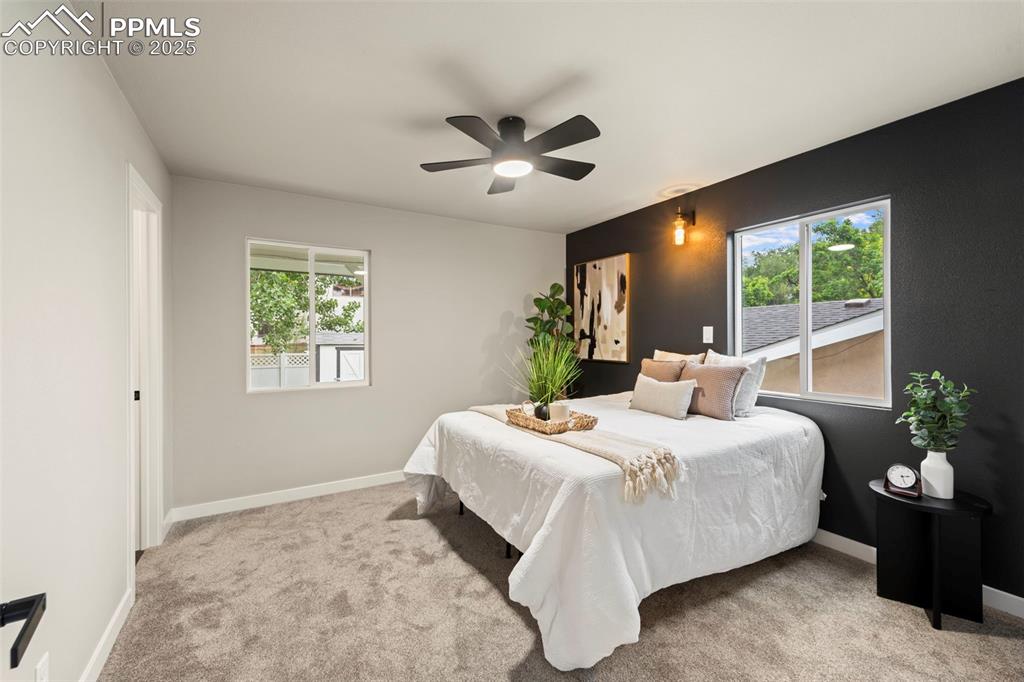 Image 18 of 31: Carpeted bedroom with multiple windows, baseboards, and ceiling fan