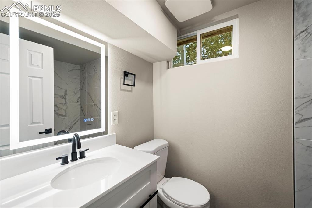 Image 24 of 31: Bathroom with toilet, vanity, and a textured wall