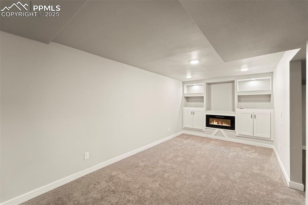 Image 30 of 31: Unfurnished living room featuring light colored carpet, baseboards, a glass