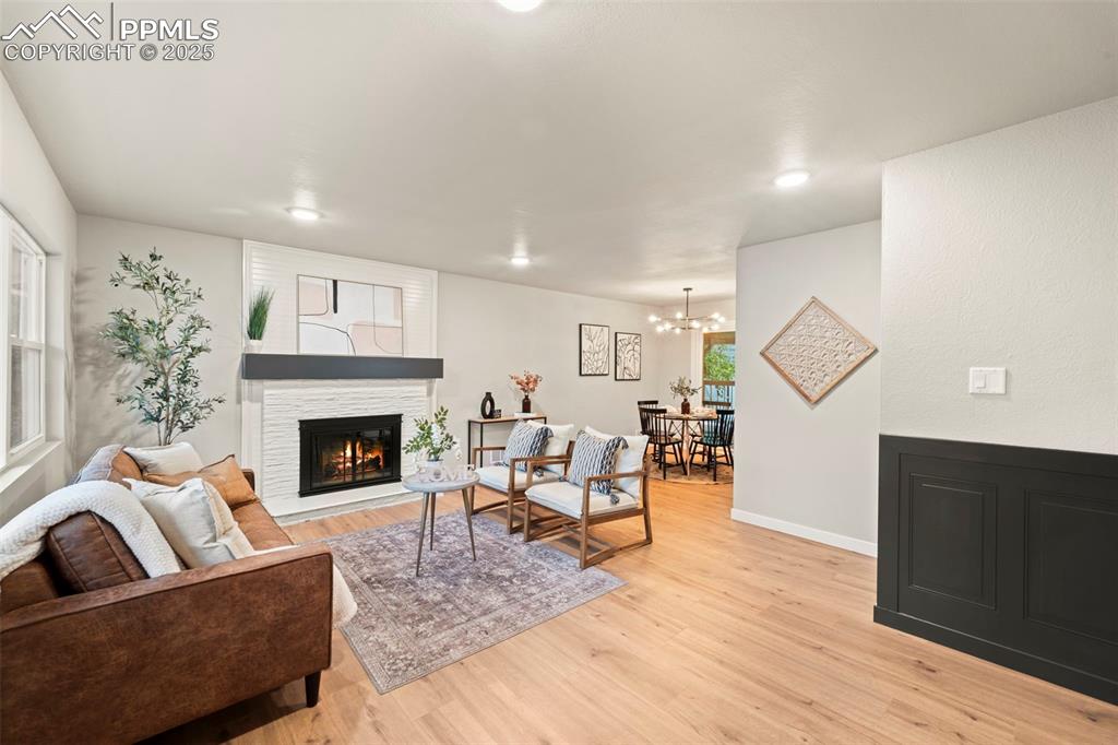 Image 9 of 31: Living room with a glass covered fireplace, light wood-type flooring, a cha