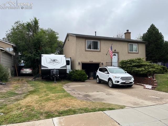 Image 5 of 17: View of front of house with stucco siding, a chimney, concrete driveway, a 
