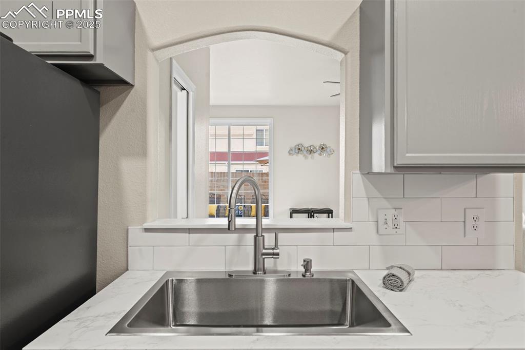 Image 10 of 42: Kitchen featuring refrigerator, decorative backsplash, light stone countert