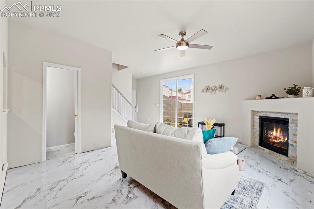 Image 11 of 42: Living room with porcelain tile with marble design flooring, ceiling fan,