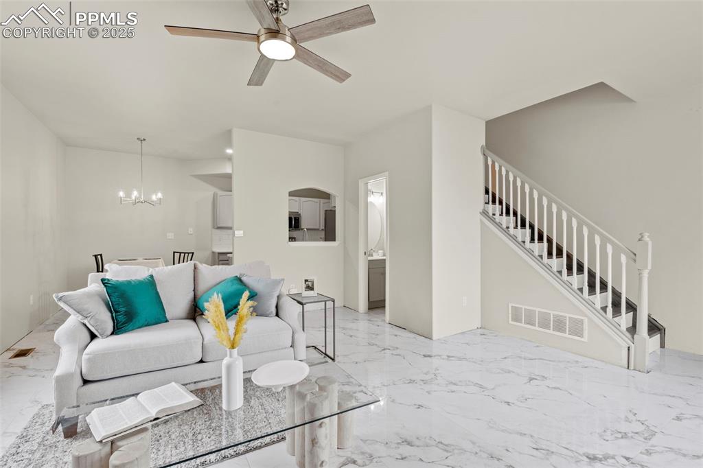 Image 12 of 42: Living room with marble design tiled flooring, ceiling fan, a chandelier, a