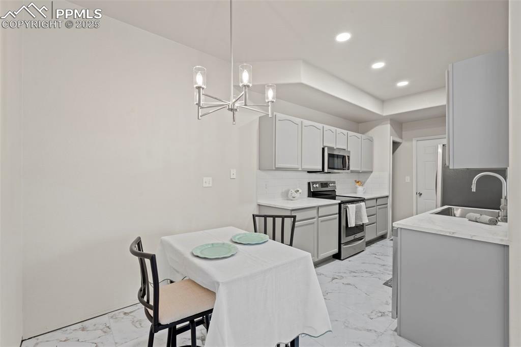 Image 14 of 42: Kitchen with tasteful backsplash, stainless steel appliances, light marble