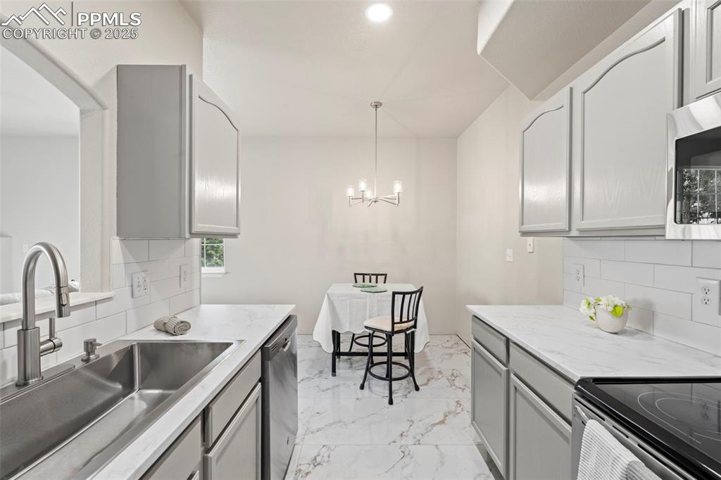 Image 16 of 42: Kitchen featuring decorative backsplash, light marble finish floors, gray c