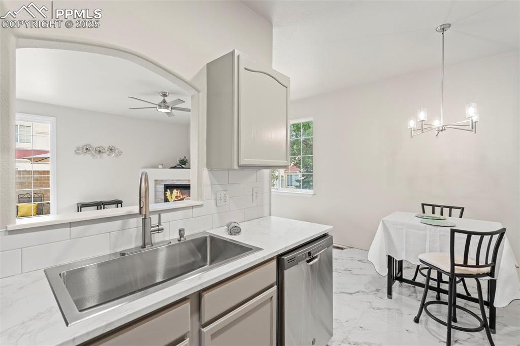 Image 17 of 42: Kitchen with tasteful backsplash, light marble finish flooring, dishwasher,