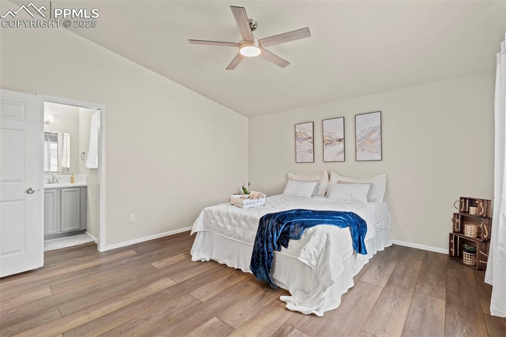 Image 20 of 42: Bedroom with vaulted ceiling, LVP floors, ensuite bath, and ceiling fan