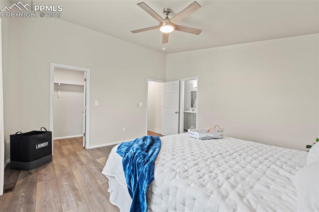 Image 22 of 42: Bedroom with LVP flooring, a spacious closet, ceiling fan, lofted ceiling,