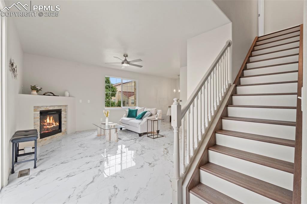 Image 4 of 42: New staircase with toeboard, a ceiling fan, and a fireplace
