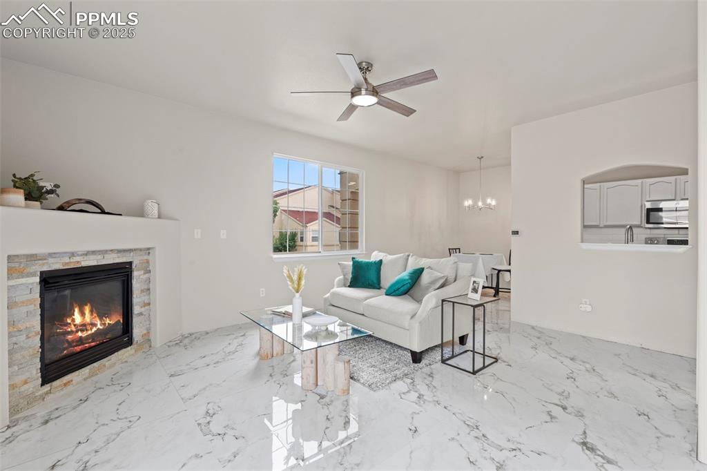 Image 5 of 42: Living area with a chandelier, porcelain tile with marble design flooring a