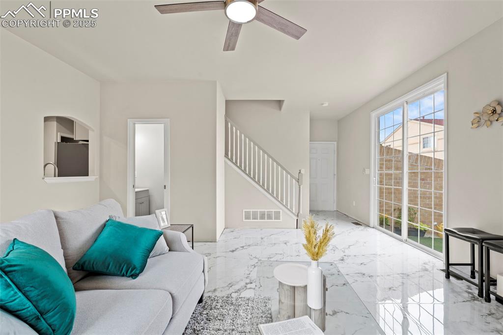 Image 6 of 42: Living room featuring porcelain tile with marble design flooring, stairway,