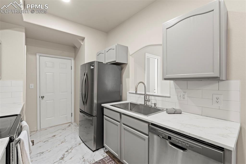 Image 9 of 42: Kitchen with decorative backsplash, stainless steel appliances, porcelain t