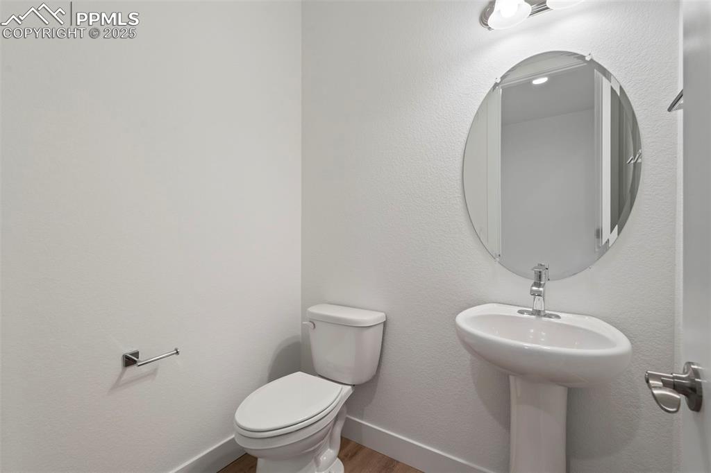 Image 33 of 34: Half bathroom with a textured wall and wood finished floors