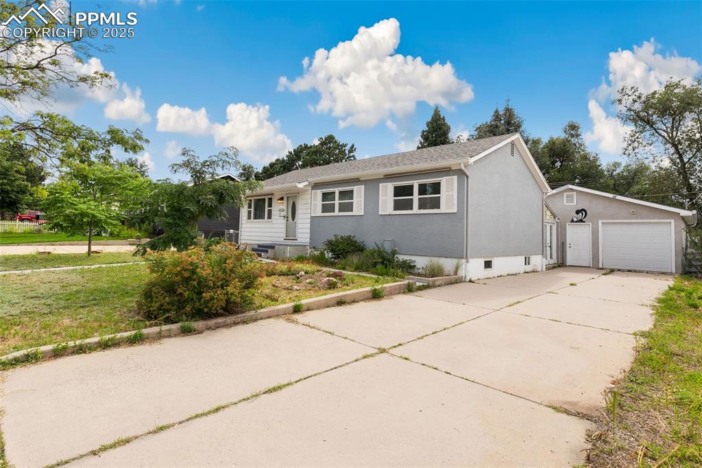 Caption: Ranch-style home with an outdoor structure, stucco siding, concrete driveway, and a front yard