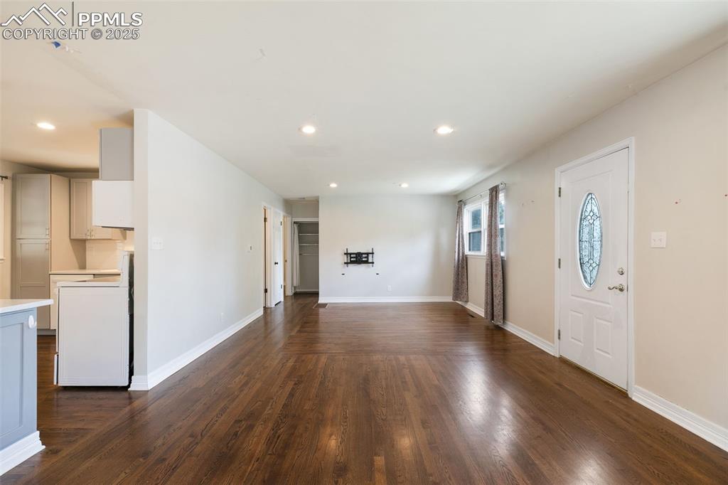 Image 13 of 36: Unfurnished living room with dark wood-style flooring and recessed lighting