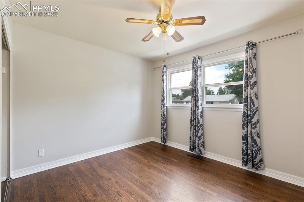 Image 18 of 36: Spare room with dark wood-style flooring and ceiling fan