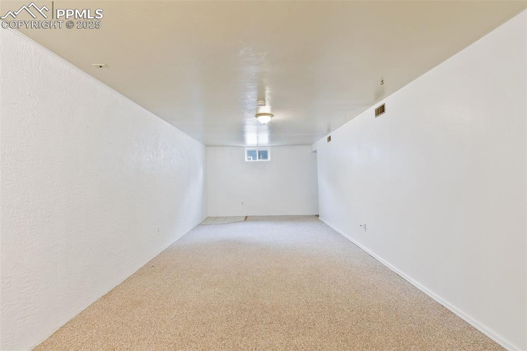Image 26 of 36: Basement featuring light colored carpet and a textured wall