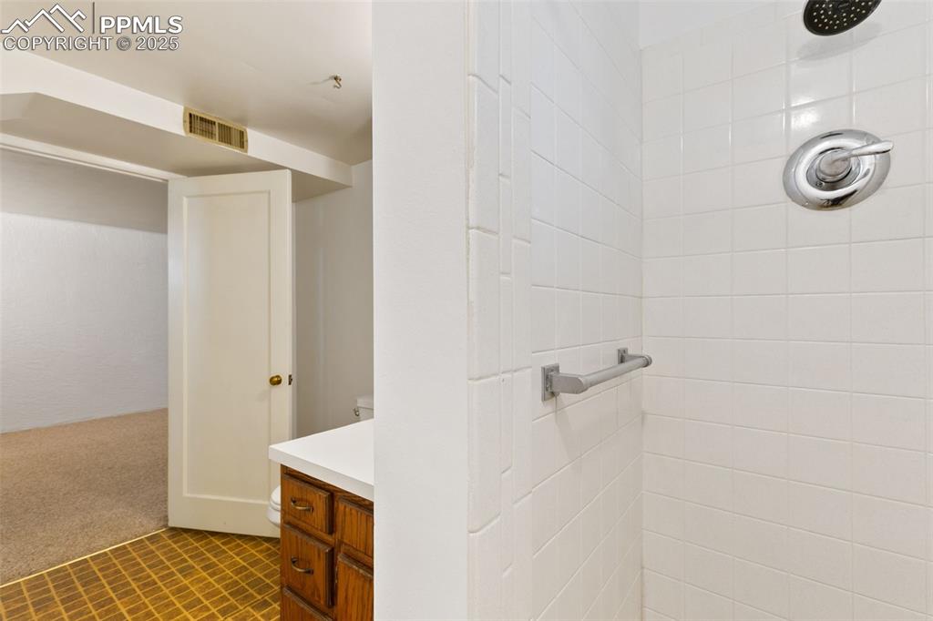 Image 29 of 36: Bathroom with tiled shower and vanity