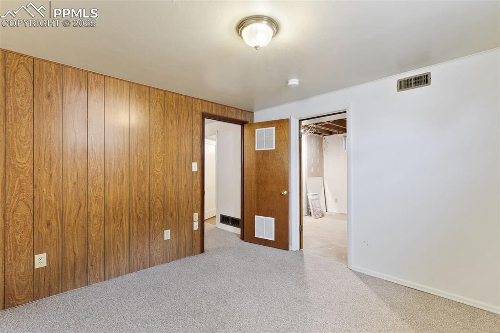 Image 30 of 36: Unfurnished bedroom featuring carpet and wood walls