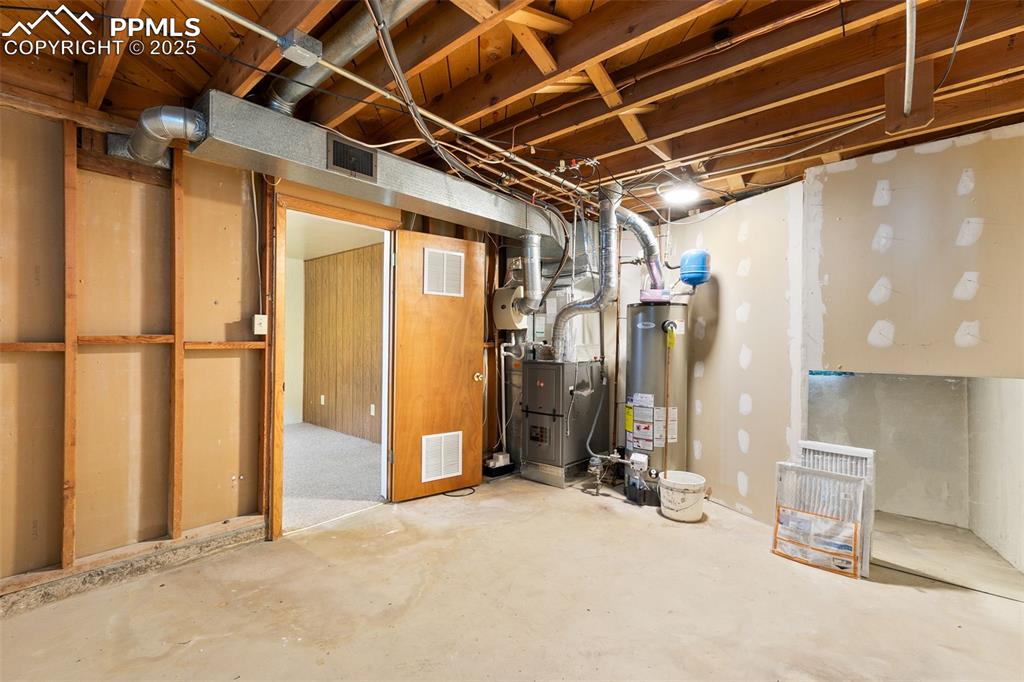 Image 33 of 36: Unfinished basement featuring water heater and heating unit