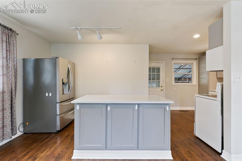 Image 4 of 36: Kitchen with stainless steel fridge, a kitchen island, washer / dryer, dark