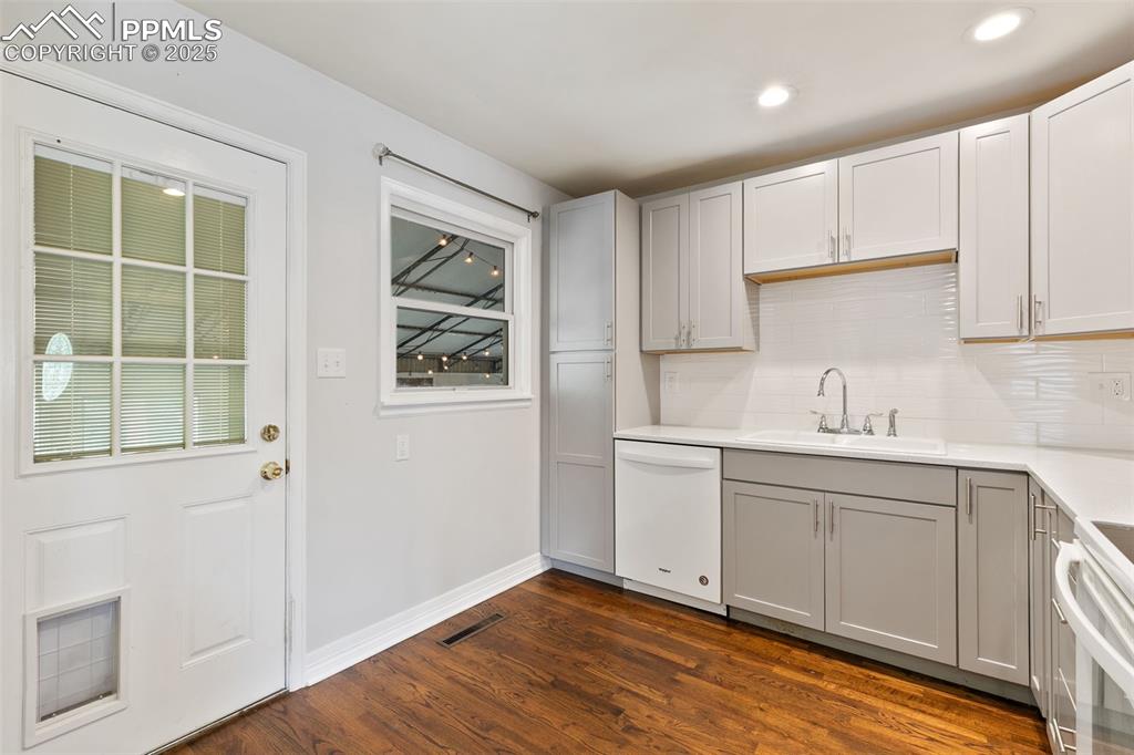 Image 5 of 36: Kitchen featuring gray cabinetry, dark wood-style floors, dishwasher, backs