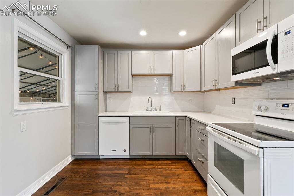 Image 7 of 36: Kitchen featuring white appliances, gray cabinets, dark wood-style flooring
