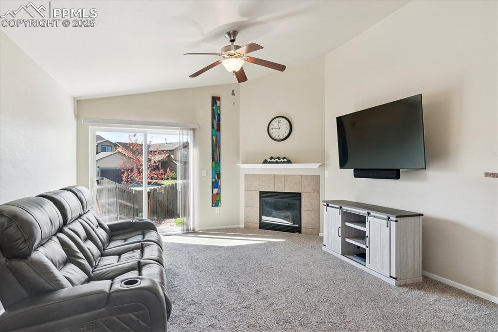Image 2 of 29: Family room area featuring lofted ceiling, carpet, a tiled fireplace, and c