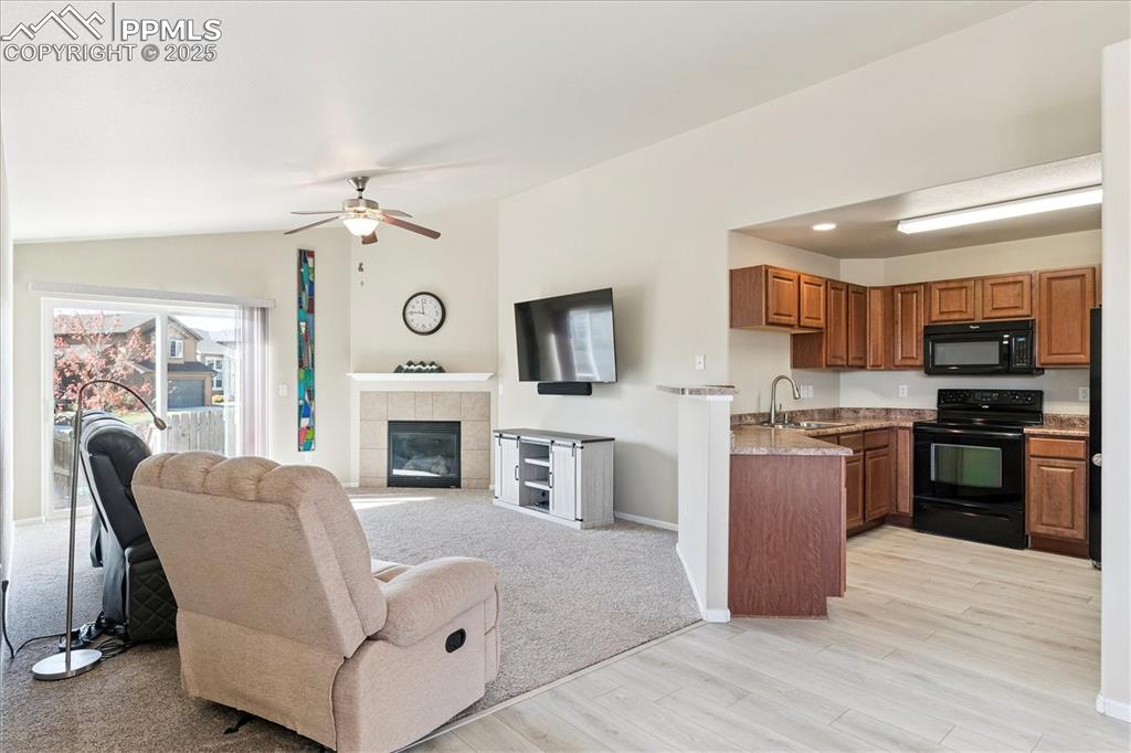 Image 3 of 29: Living area featuring a tile fireplace, ceiling fan, light wood finished fl