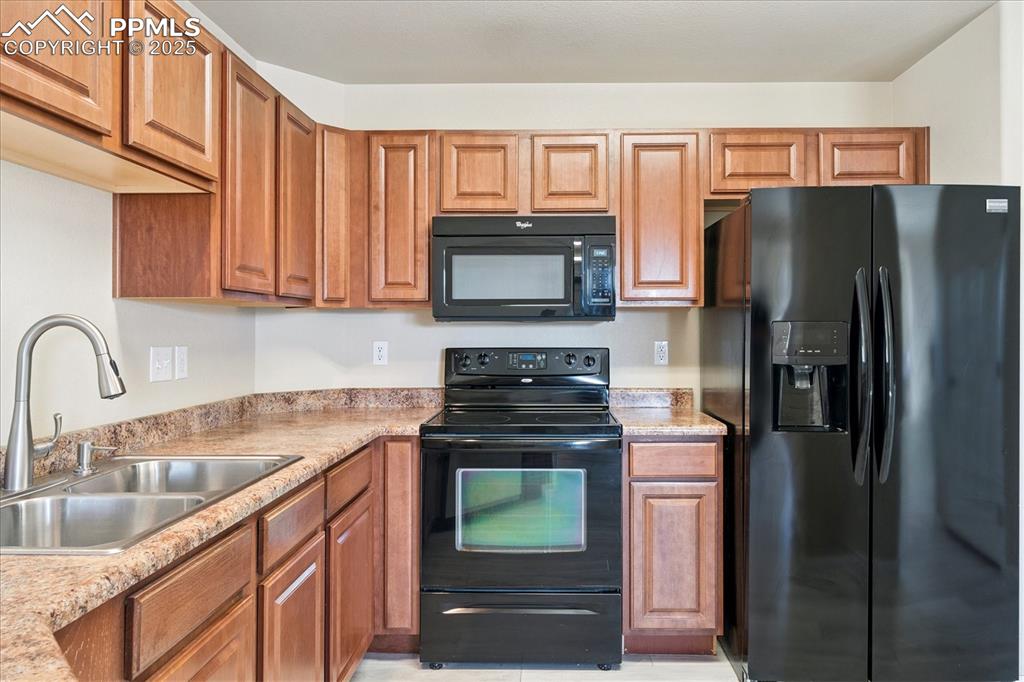 Image 5 of 29: Kitchen featuring black appliances and brown cabinets