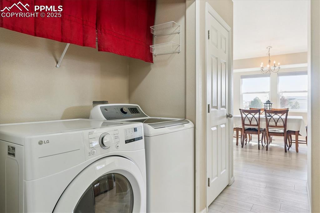 Image 6 of 29: Laundry area with a chandelier, light wood-style floors, and independent wa