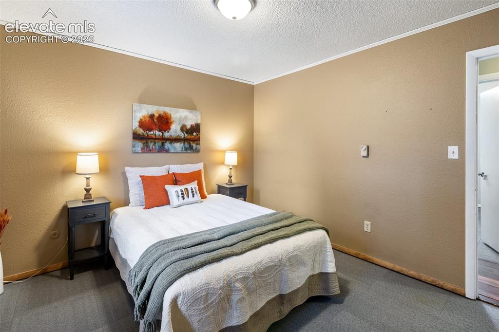 Image 14 of 41: Bedroom featuring textured tan walls and gray carpet flooring