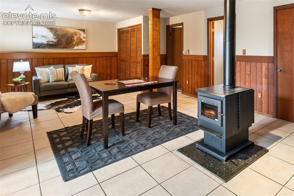 Image 21 of 41: Freestanding black wood stove with a stone hearth, set against light-colore