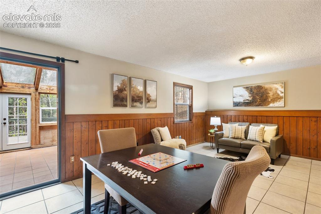 Image 22 of 41: Versatile room featuring wood paneling, light-toned walls, and a sliding gl